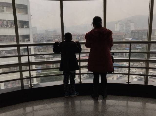 11月24日，在张家界市人民医院住院楼，张小宝接受尿道治疗后，和妈妈站在窗前。