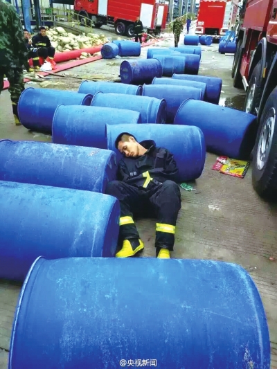 大火扑灭后，精疲力尽的消防战士蜷缩在地上睡去。