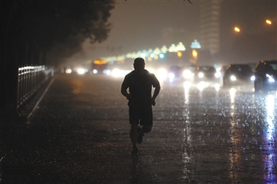 8月11日傍晚,一场急雨降临,一位北京市民在雨中奔跑图/视觉中国