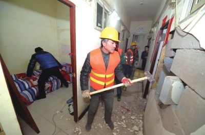 工人对地下室进行强拆，旁边的租户收拾行李。